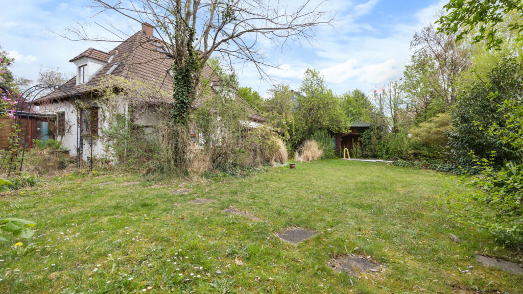 Garden of the property in Großhadern with a rose arch, ivy-covered house, and lawn area