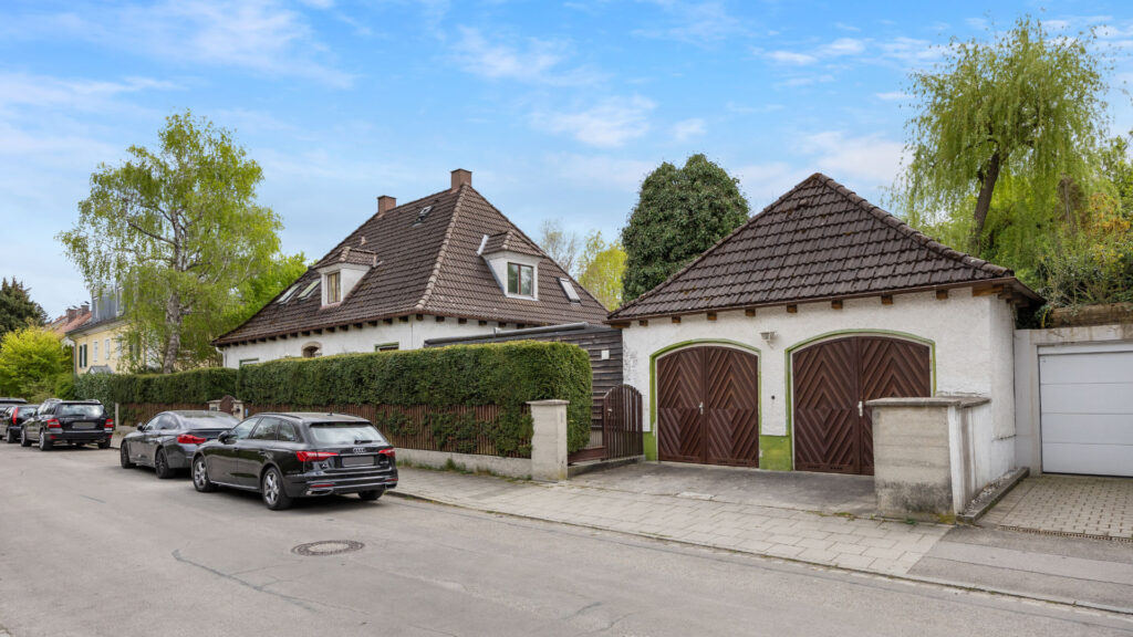 Street view of the property in Großhadern with the existing old house, double garage, and parked cars