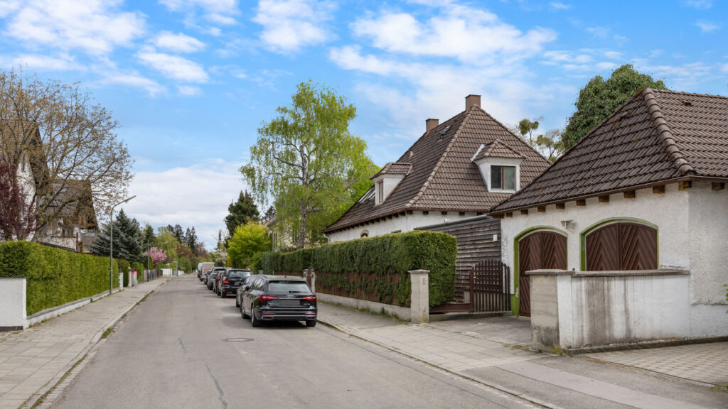 Quiet street in Großhadern with an older villa, double garage, and dense hedge planting