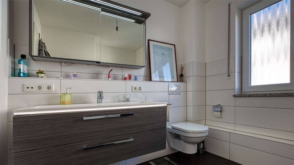 Modernes Badezimmer mit großem Waschtisch, Spiegelschrank und Fenster in der Wohnung in München-Hadern