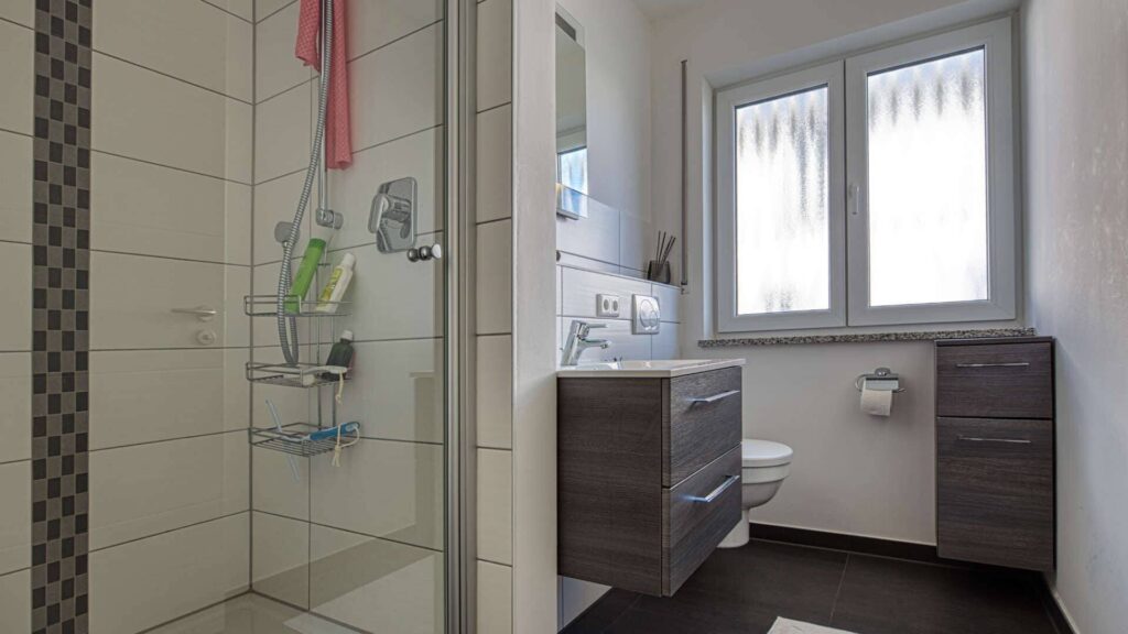 Modernes Badezimmer mit Duschkabine, WC und dunklem Fliesenboden in der Wohnung in München-Hadern