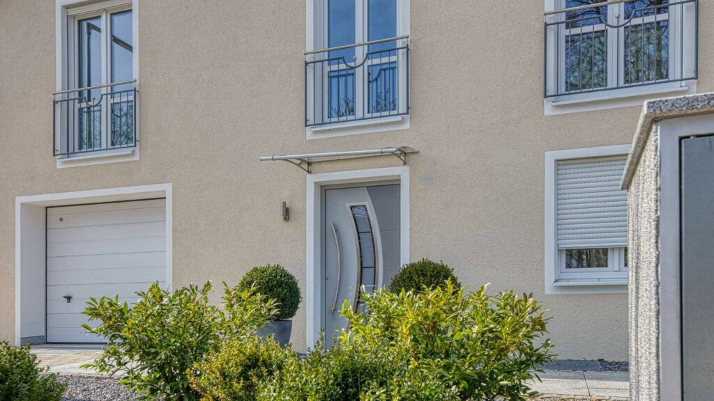 Moderner Hauseingang mit Garage und geschnittenen Sträuchern der Wohnanlage in München-Hadern
