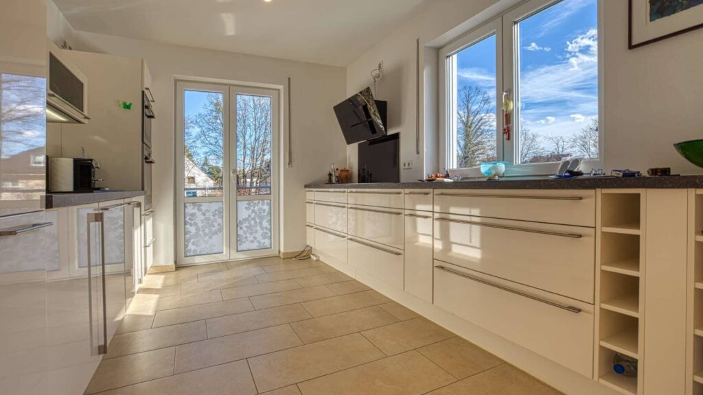 Moderne Einbauküche mit heller Arbeitsplatte und großer Fensterfront in der Wohnung in München-Hadern