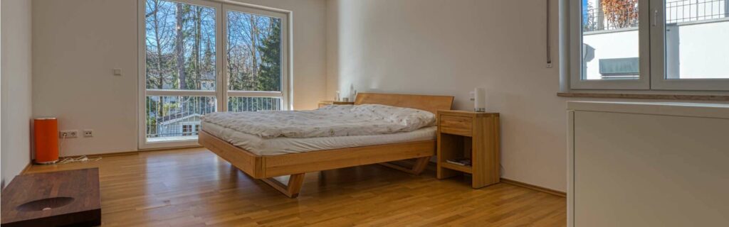 Schlafzimmer mit Doppelbett und Zugang zum Balkon in einer Wohnung in München-Hadern