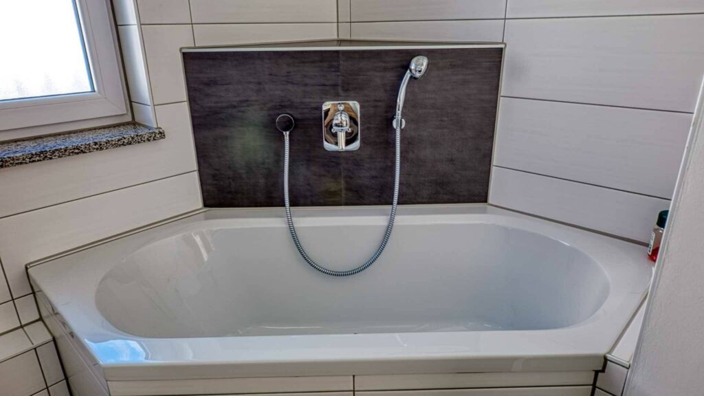 Eingebaute Badewanne mit dunklen Fliesenakzenten im Bad der Wohnung in München-Hadern