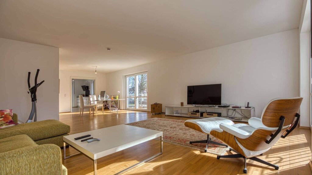 Möbliertes Wohnzimmer mit Designerstühlen, Ledersofa und großem TV in der Wohnung in München-Hadern