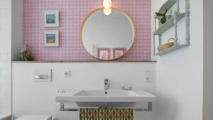 Bathroom of the old Haidhausen apartment with pink wallpaper, round mirror, floral pictures and light blue wall shelf
