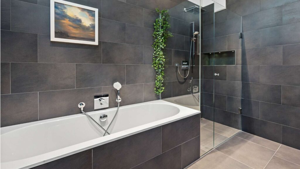 Modernes Badezimmer mit dunklen Fliesen, Badewanne und Glasdusche in Altbauwohnung Haidhausen