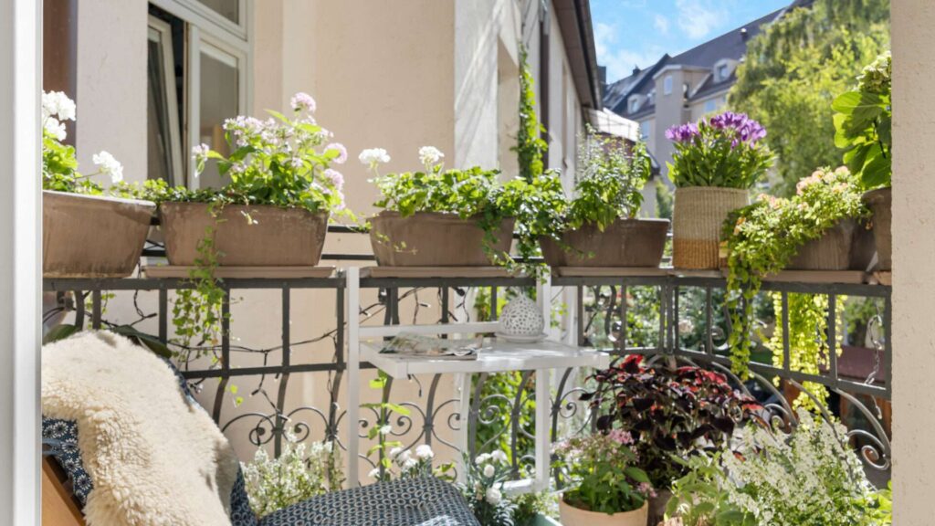 Balkon der Altbauwohnung Haidhausen mit Blumenkästen am Geländer und Blick über die Münchner Dächer