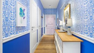 Sprawling view into the blue-papered hallway of the old building apartment in Haidhausen with a pink door and wall console