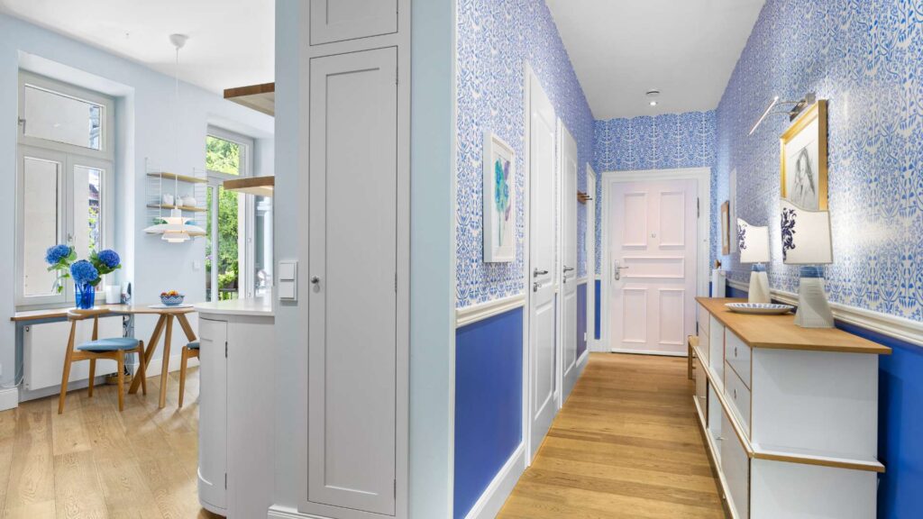 Übergang von der blau tapezierten Diele zur offenen Küche in der Altbauwohnung Haidhausen