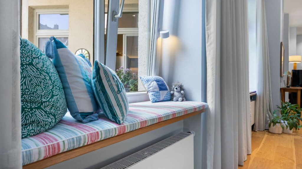 Gepolsterte Fensterbank mit gemusterten Kissen in einer Altbauwohnung in München-Haidhausen