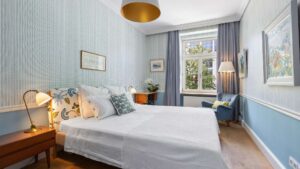 Bedroom with double bed and bedside lamp, another view in a period apartment in Haidhausen