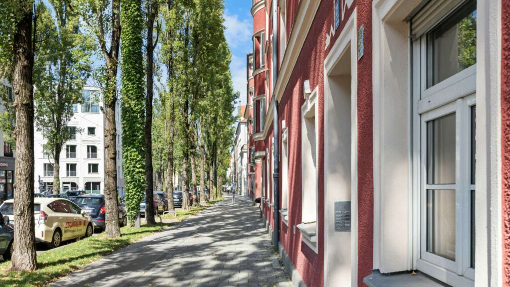 Baumbestandene Altbaustraße mit rot verputzten Fassaden im Münchner Stadtteil Haidhausen