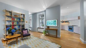 Living area with bookshelf and view into the open kitchen in a Haidhausen old-style apartment