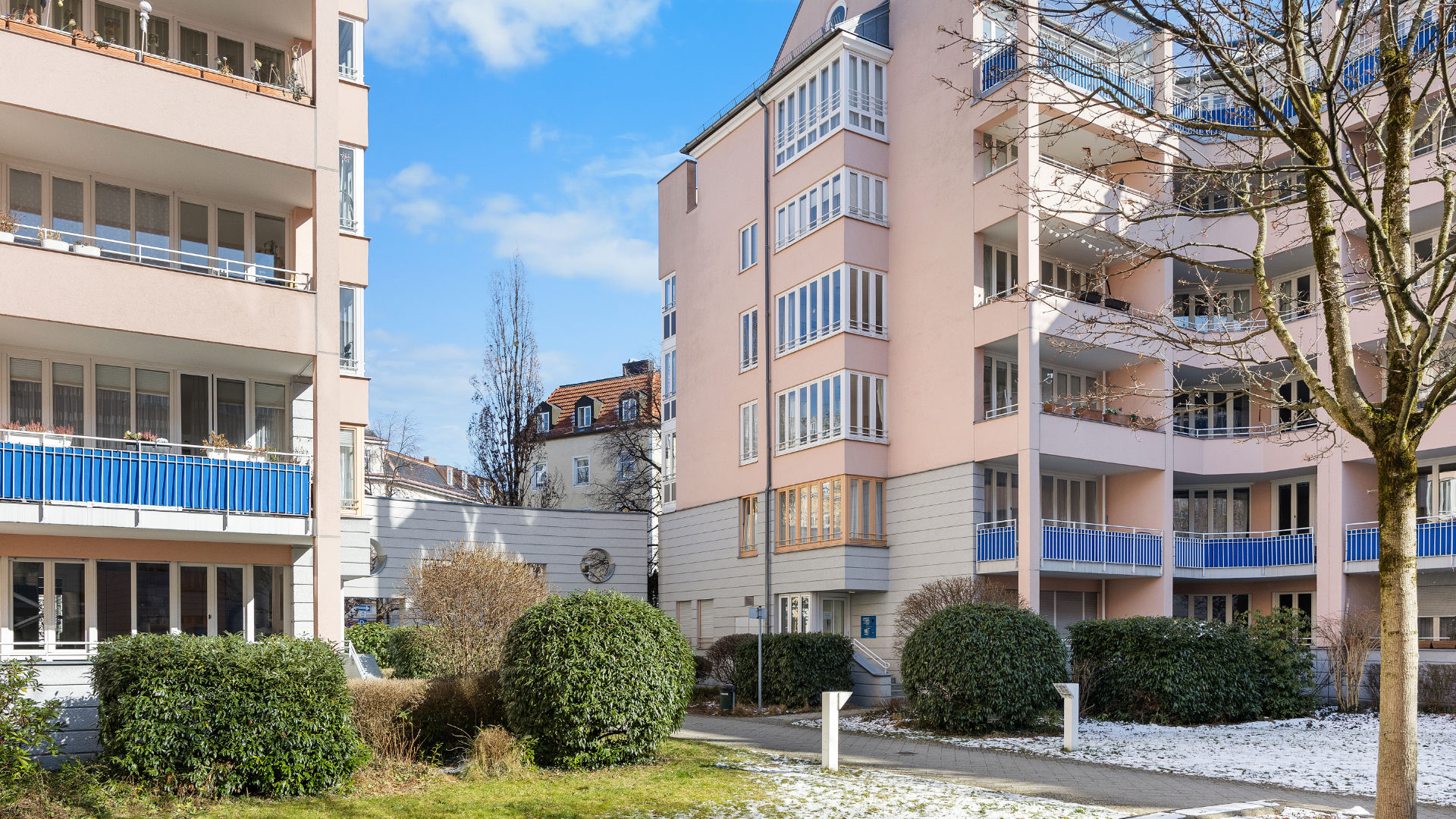 Multi-story residential complex with a pink and cream-colored facade and a landscaped inner courtyard in Munich-Haidhausen