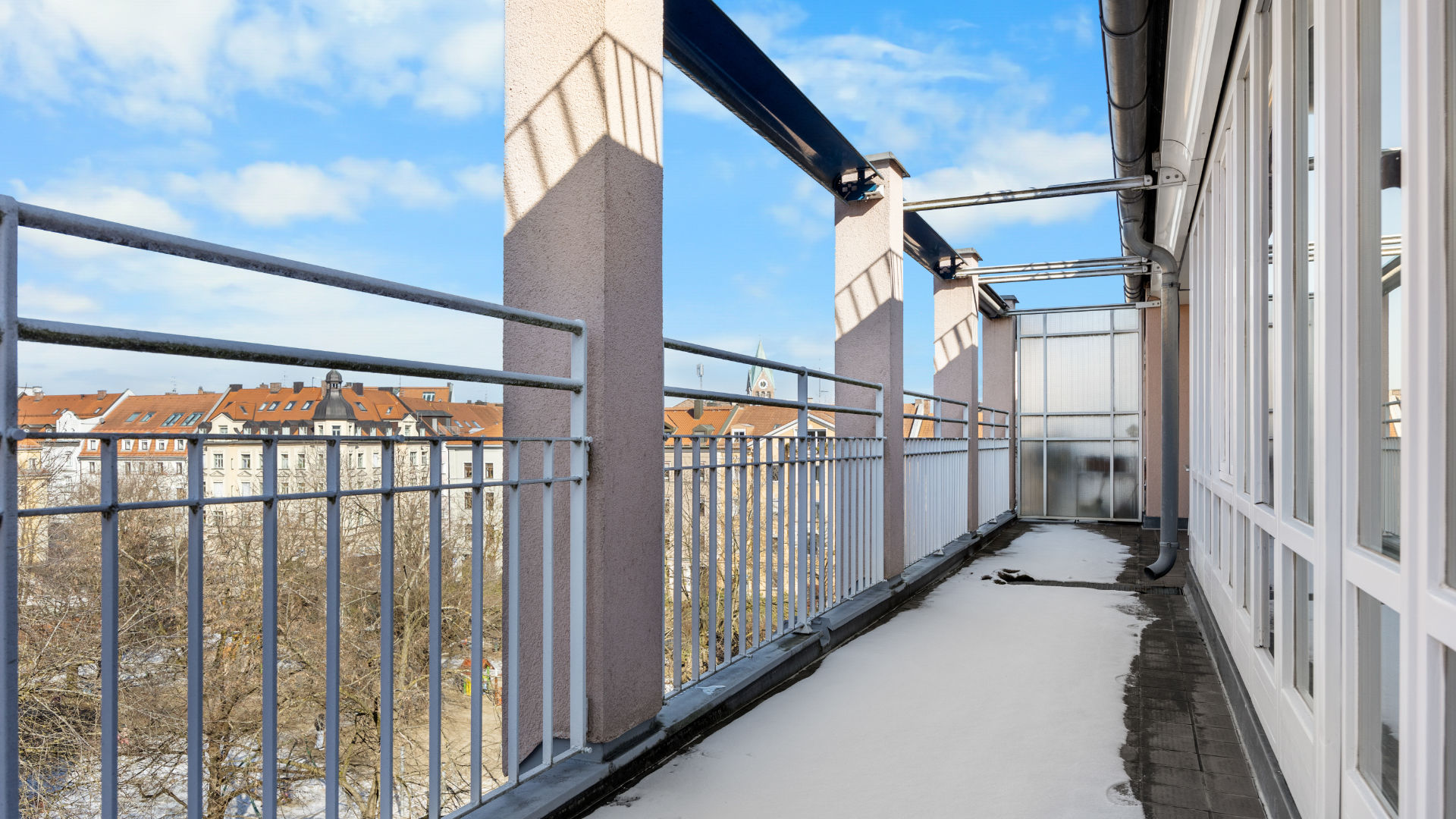 Wrap-around roof terrace with metal railing and panoramic views of Munich from apartment in Haidhausen
