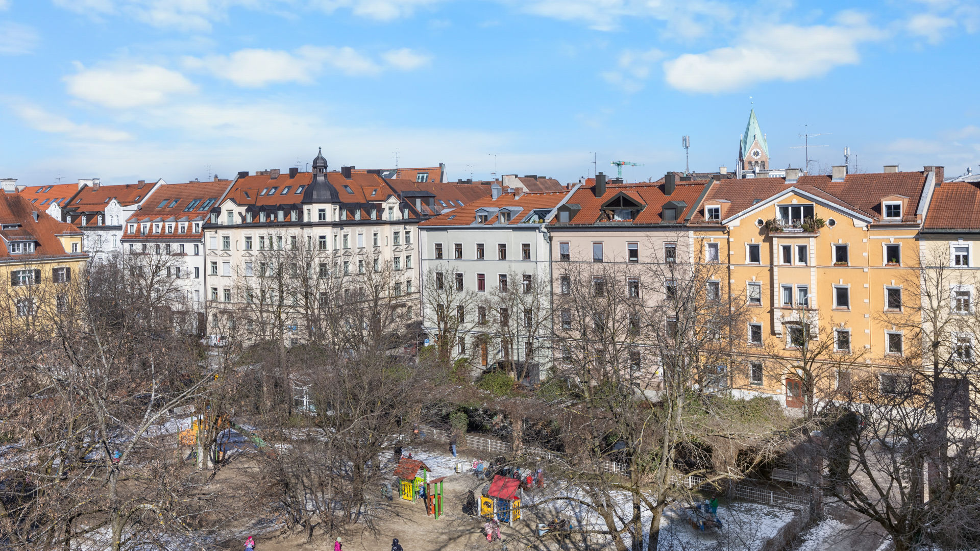 Panoramic view over Munich rooftops with a church tower seen from a rooftop terrace in Haidhausen