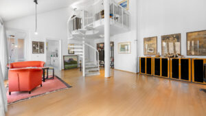 Loft-style living room with a gallery staircase and a red armchair in an apartment in Munich-Haidhausen