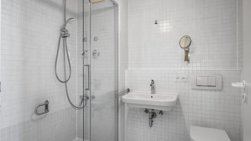 Tiled bathroom with shower cabin, sink, and toilet in Munich Isarvorstadt rental apartment