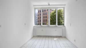 Empty kitchen with tile floor and window overlooking trees in an apartment for rent in Munich Isarvorstadt