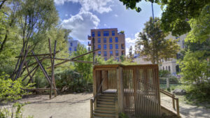 Nature-oriented playground with a wooden hut and climbing elements among trees near Munich-Isarvorstadt