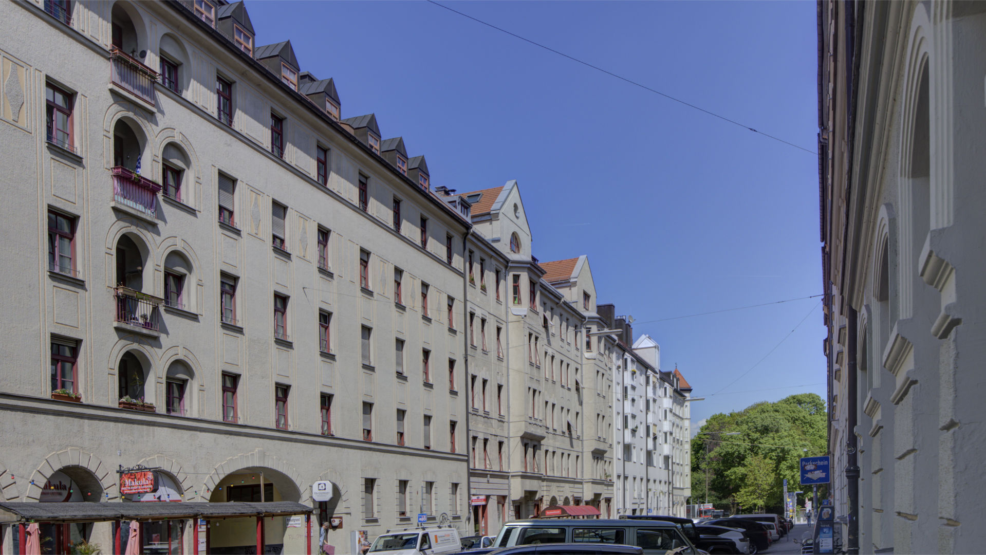 Street with bright old building facades and parked cars in Munich's Isarvorstadt district in the sunshine
