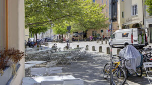 Sunny street scene with café tables, bicycles, and historic building facades in Munich's Isarvorstadt district