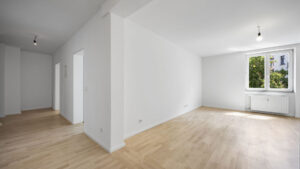 Empty open living area with doorway, window, and light hardwood floor in Munich Isarvorstadt rental apartment