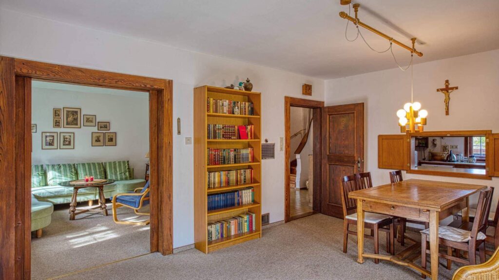 Gemütliches Esszimmer mit Holztisch, Bücherregal und Kruzifix im Haus in Kochel am See