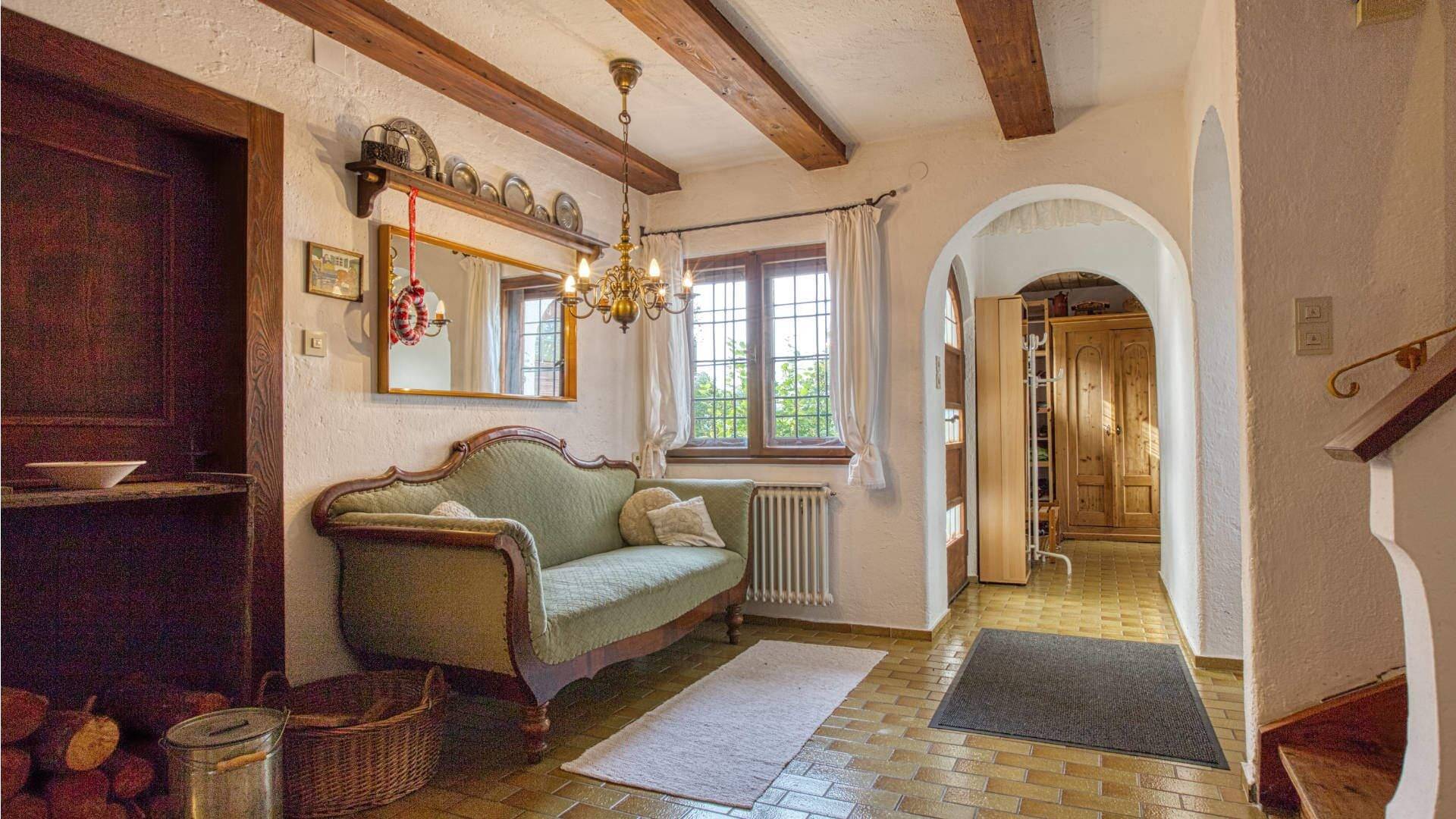 Rustikale Diele mit Holzbalken und antikem Sofa in einem Landhaus in Kochel am See