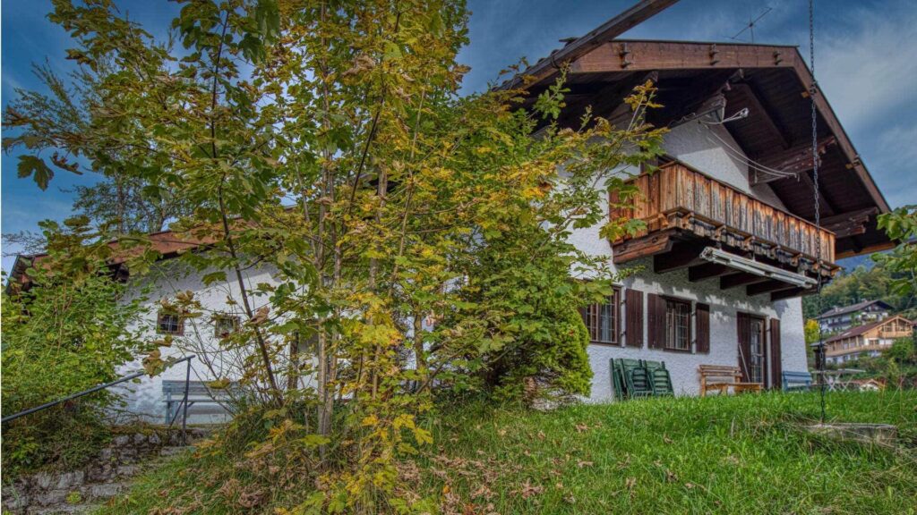 Bayerisches Landhaus mit hölzernem Balkon und herbstlich gefärbten Bäumen in Kochel am See