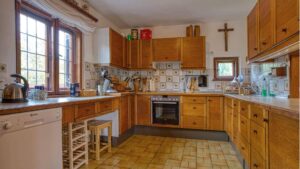 Rustikale Einbauküche mit Holzfronten und Kachelboden im Ferienhaus in Kochel am See