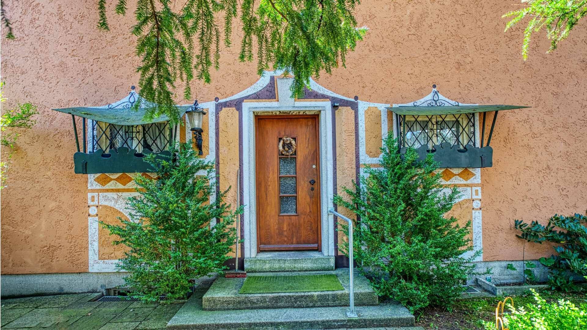 Artistically painted entrance with carved wooden door and bay windows on the property in Munich-Laim