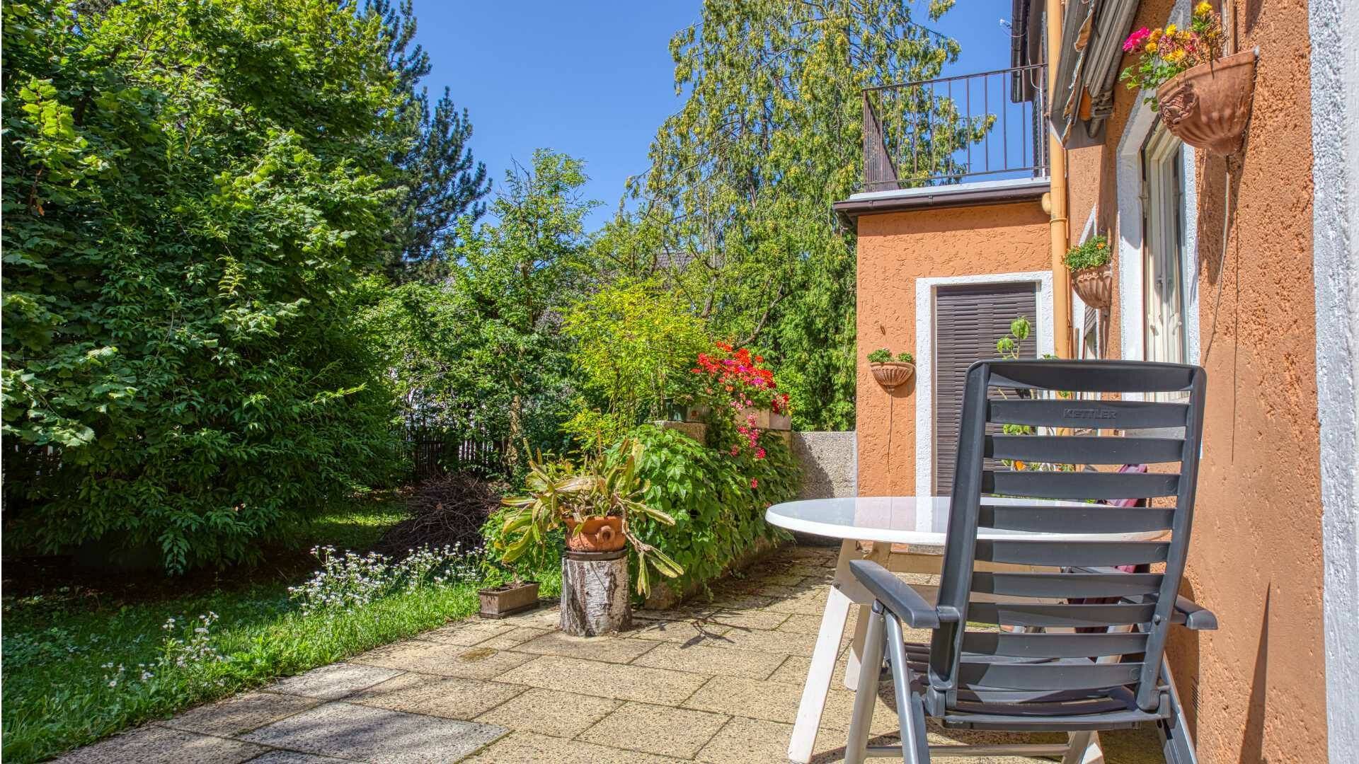 Sunny terrace with seating and blooming plants on the property in Munich-Laim