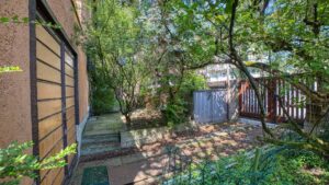 Shady garden path with a wooden fence and dense vegetation on the property in Munich-Laim