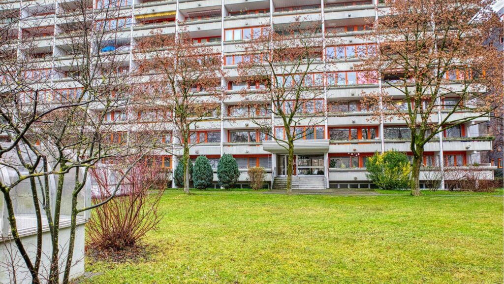 Außenansicht des mehrstöckigen Wohnhauses mit Rasenfläche in München-Laim