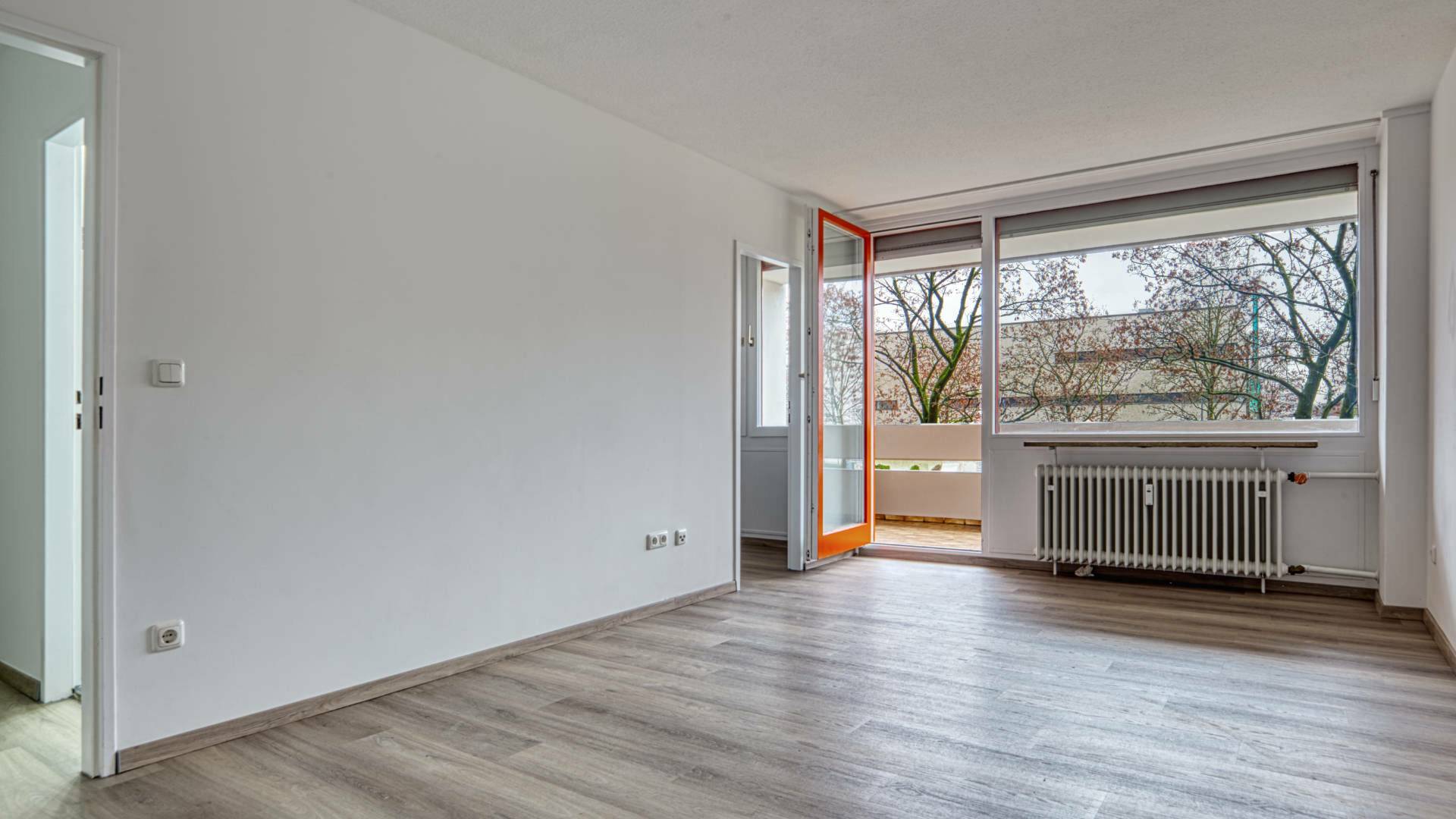 Leeres Zimmer mit Balkonzugang und hellem Boden in einer Wohnung in München-Laim