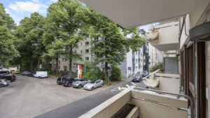 View from the balcony of parked cars, trees, and residential buildings in Munich-Lehel