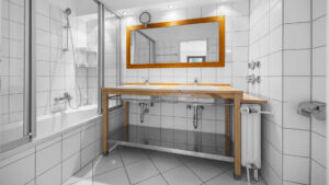 Older bathroom with wooden vanity, mirror, and bathtub with shower screen in Munich-Lehel
