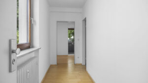 Empty hallway with window, door handle, and view through to the kitchen in a rental apartment in Munich-Lehel