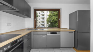 Gray fitted kitchen with wooden countertop, window, and refrigerator in Munich-Lehel rental apartment