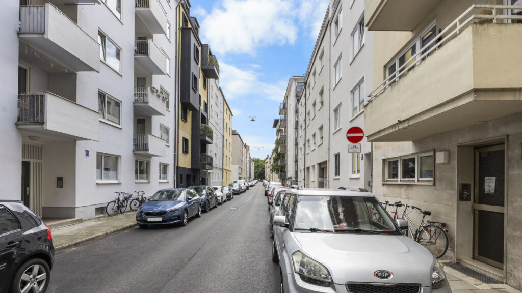 Straße mit Einbahnstraßenschild, geparkten Autos und Wohngebäuden in München-Lehel