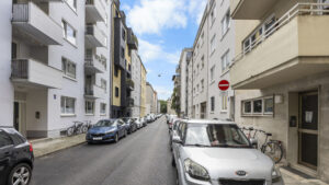 Street with one-way sign, parked cars, and residential buildings in Munich-Lehel