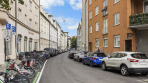 Street with parked cars, bicycles, and old building facades in various colors in Munich-Lehel
