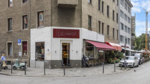 Traditional brick-and-mortar store with a red awning on a street corner in Munich-Lehel