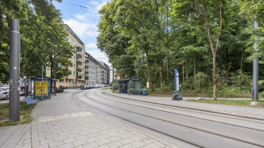Straße mit Straßenbahngleisen, Bäumen und Wohngebäuden im Stadtteil München-Lehel