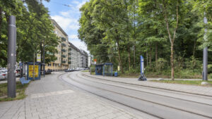 Street with tram tracks, trees, and residential buildings in the Munich-Lehel district