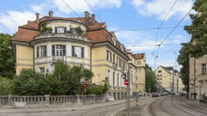 Historic villa with a small turret and tile roof on a street with tram tracks in Munich-Lehel