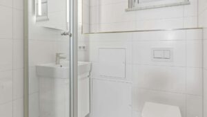 Compact shower room in Lerchenau with a glass shower, washbasin, and white tiles.